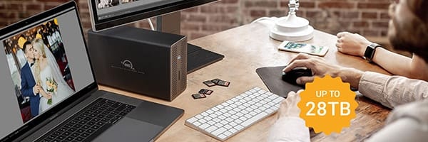 Picture of an OWC Mercury Elite Pro Dock on a desk near a MacBook Pro