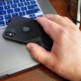 Man picking up iPhone from computer
