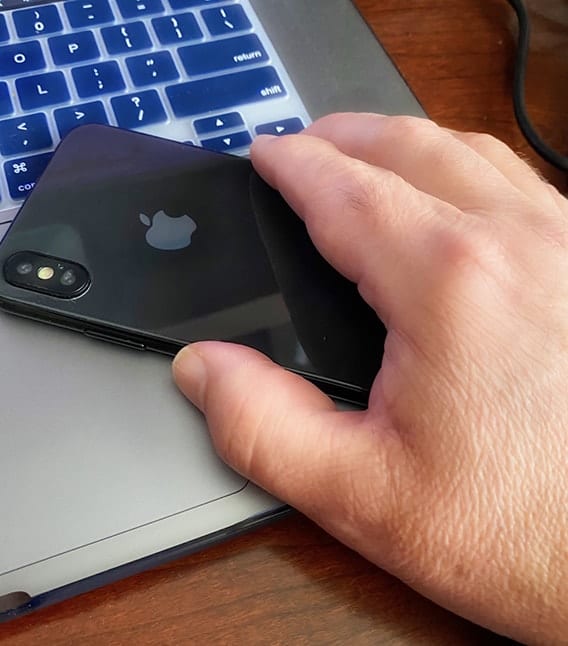 Man's hand picking up iphone from computer
