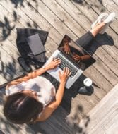 woman working outside on deck with laptop