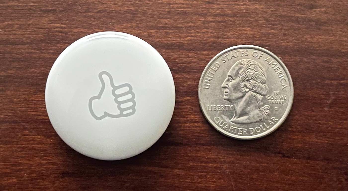 An Apple AirTag next to a US quarter dollar coin