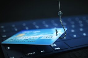 Blue credit card on computer keyboard on a phish hook - fraud alert email scam