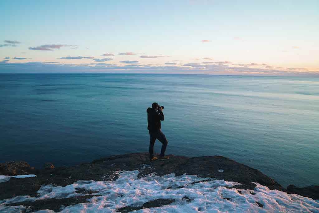 man on cliff holding camera