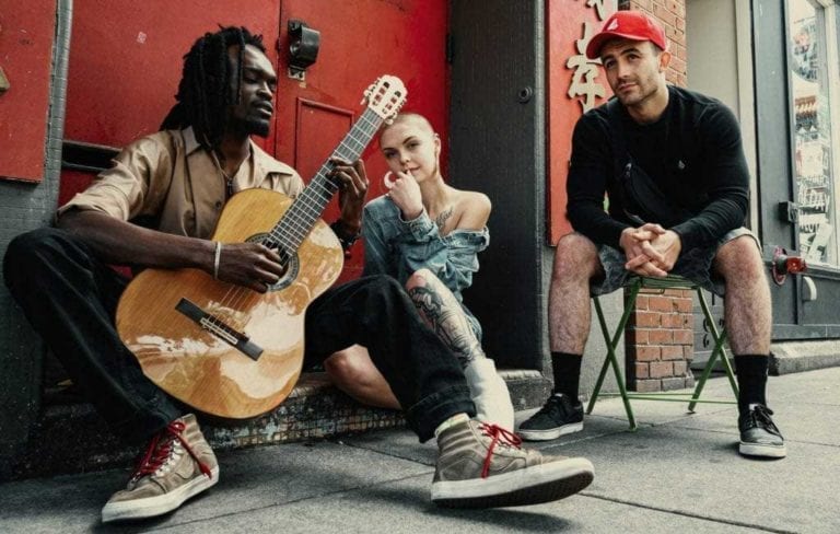 three people sitting and playing guitsr